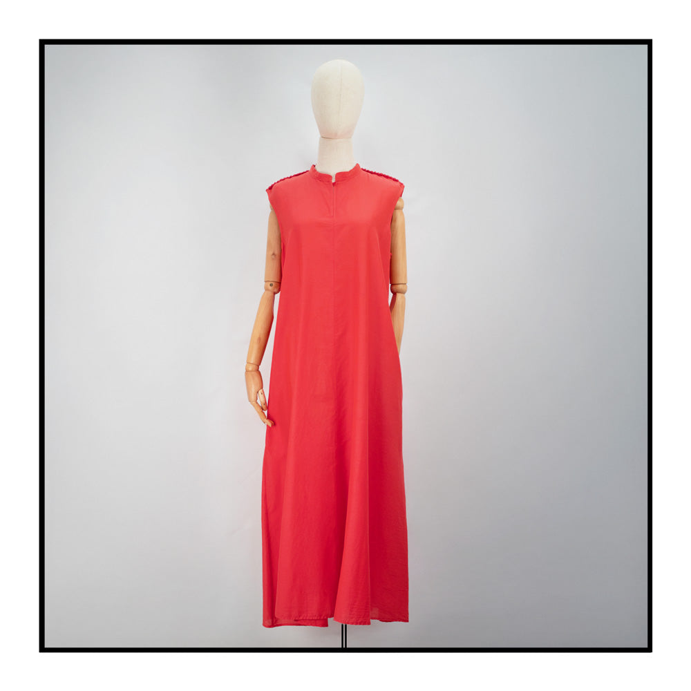 Mannequin view of a loose fit of the elegant red long sleeveless dress with a standing collar, crafted from 80% cotton and 20% silk, featuring Antonello Tedde's distinctive pom detail design, a flowing silhouette, hidden pockets, and a matching belt for versatile styling.