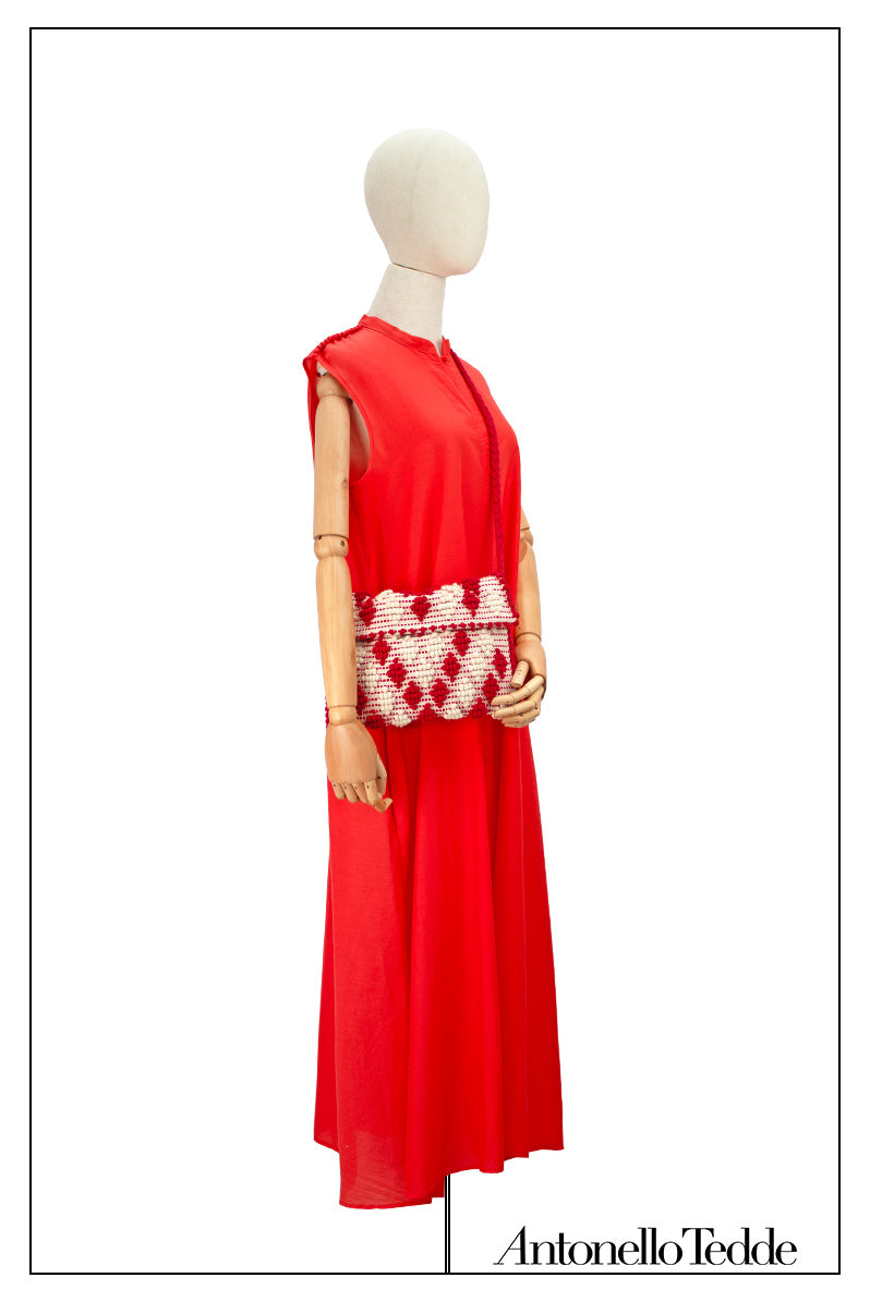 Front view without the belt of an elegant red long sleeveless dress with a standing collar on a model, crafted from 80% cotton and 20% silk, featuring Antonello Tedde's distinctive pom detail design, a flowing silhouette, hidden pockets, and a matching belt for versatile styling.