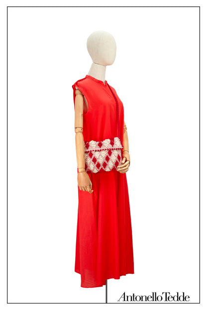 Front view without the belt of an elegant red long sleeveless dress with a standing collar on a model, crafted from 80% cotton and 20% silk, featuring Antonello Tedde's distinctive pom detail design, a flowing silhouette, hidden pockets, and a matching belt for versatile styling.