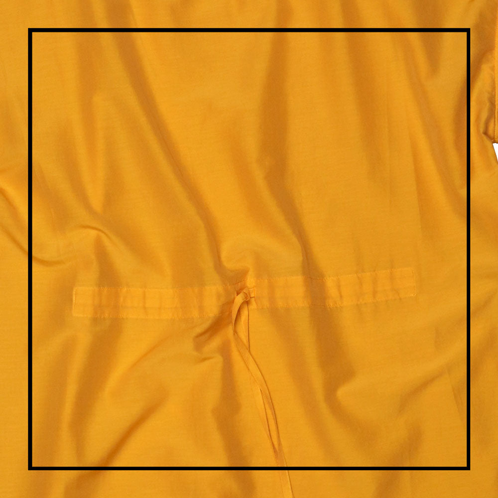 Mustard yellow cover-up dress with round collar, pom details on the collar and sleeve edges, adjustable drawstring waist belt, crafted from 80% cotton and 20% silk, designed for lightweight comfort and elegance.