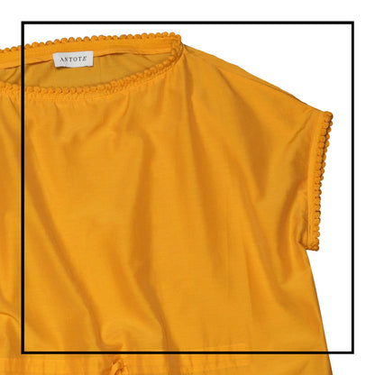 Mustard yellow cover-up dress with round collar, pom details on the collar and sleeve edges, adjustable drawstring waist belt, crafted from 80% cotton and 20% silk, designed for lightweight comfort and elegance.