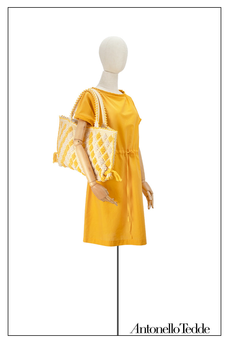 Mustard yellow cover-up dress with round collar, pom details on the collar and sleeve edges, adjustable drawstring waist belt, crafted from 80% cotton and 20% silk, designed for lightweight comfort and elegance, with capriccioli small diamond tote in yellow and cream 