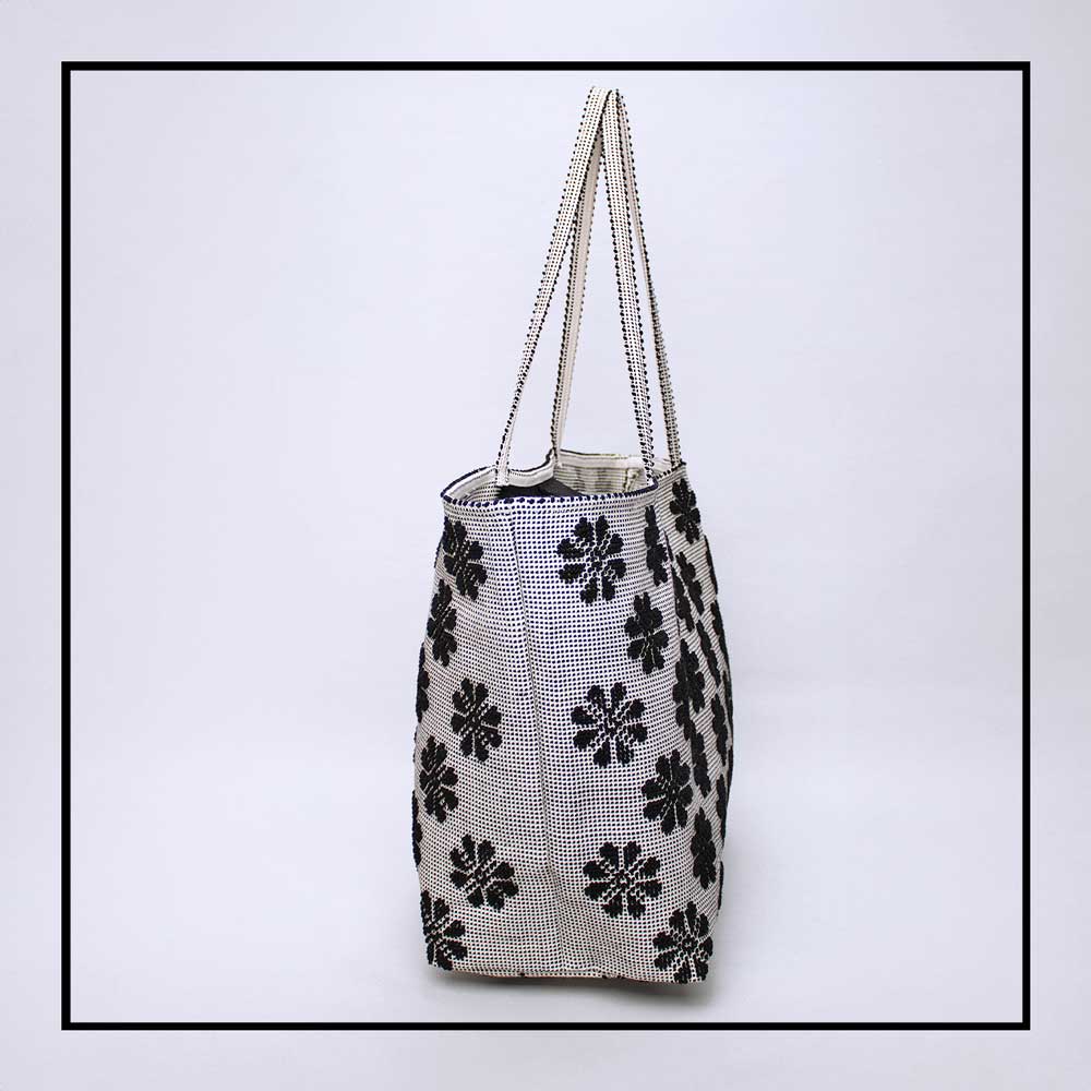 Side view of a black and white tote bag with a daisies pattern. Main view of our Sustainable tote - summer bag - luxury handbag - handwoven made in Italy by hand  - timeless individualistic fashion • eco-friendly fashion • socially responsible, lasting fashion.