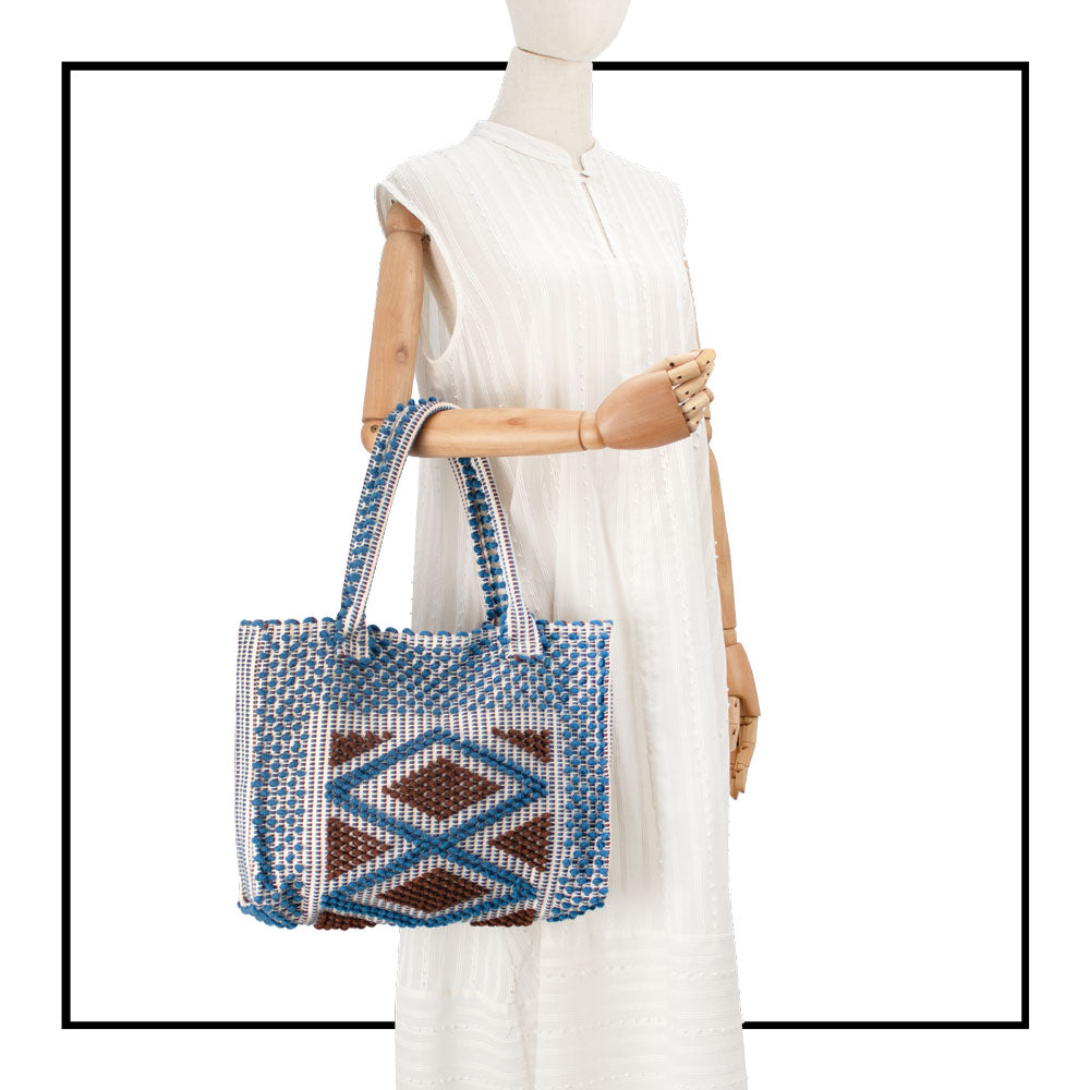 Cream sleeveless dress with a standing collar, crafted from 100% Khadi cotton handwoven in India, featuring a flowing design with hidden pockets and a matching belt for versatile styling. Paired here with a denim and hazelnut handbag. 