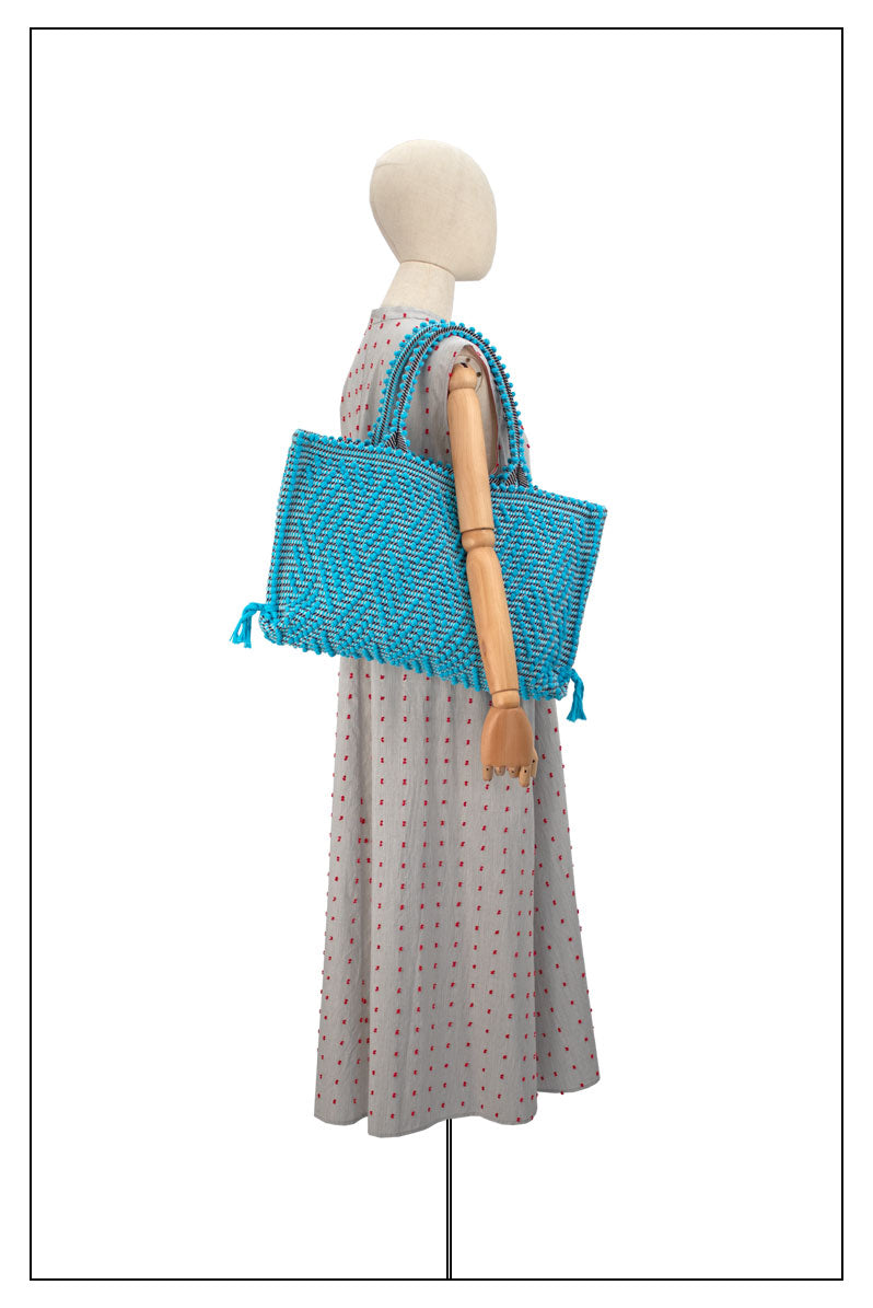 Medium tote bag turquoise and black with diamond pattern on a model for proportions it is a winter or summer bag - luxury handbag - handwoven tote made in Italy by hand • timeless individualistic fashion • eco-friendly fashion • socially responsible, lasting fashion